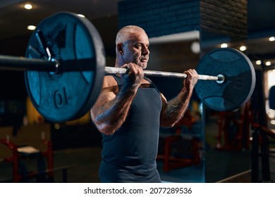 Bodybuilder older athlete trains in the gym while pumping up biceps muscles. Sporty muscular guy with barbell. Sport and fitness . Individual sports recreation. - Powered by Shutterstock