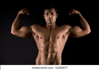 Bodybuilder posing on black background.