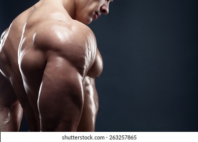 Bodybuilder showing his back and biceps muscles, personal fitness trainer. Strong man flexing his muscles