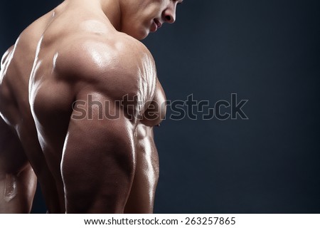 Bodybuilder showing his back and biceps muscles, personal fitness trainer. Strong man flexing his muscles