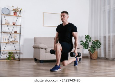 Bodybuilder training at home, doing lunges with dumbbells. Young man performing physical exercises in his living room. Close up, copy space, background. - Powered by Shutterstock