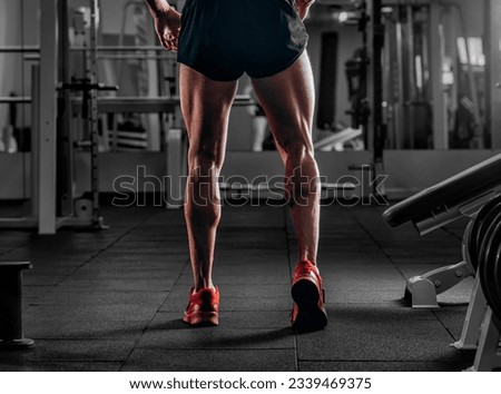 Bodybuilders muscular calf legs. Athlete man doing workout exercise in gym
