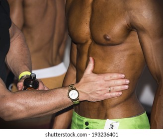 Bodybuilding Competition Backstage: Contestant Being Oiled And Fake Tan Applied To Skin