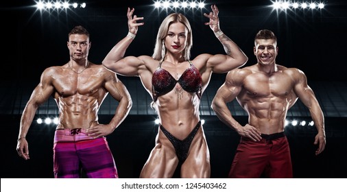 Bodybuilding Competitions On The Scene. Men And Women Sportsmens And Athletes. Black Background With Lights.