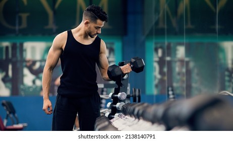 Bodybuilding Concept. Portrait Of Muscular Young Arab Man Training With Dumbbells At Gym, Confident Middle Eastern Bodybuilder Working Out With Light Weights In Sport Club, Panorama, Copy Space