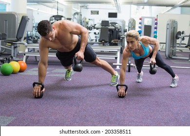 Bodybuilding Man And Woman Lifting Kettlebells In Plank Position At The Gym