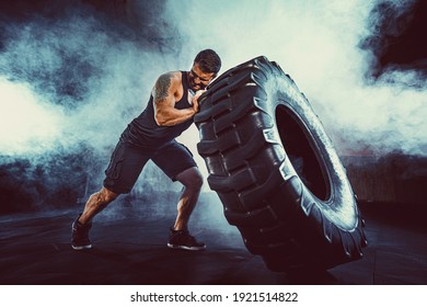 Bodybuilding training, bearded strong sportsman with muscular body lifting heavy wheel in gym. - Powered by Shutterstock