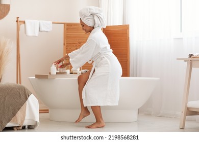 Bodycare Cosmetics. Happy Black Lady Using Liquid Soap Or Body Lotion Sitting On Bathtub In Modern Bathroom Indoors. Selfcare And Spa, Beauty Routine Concept