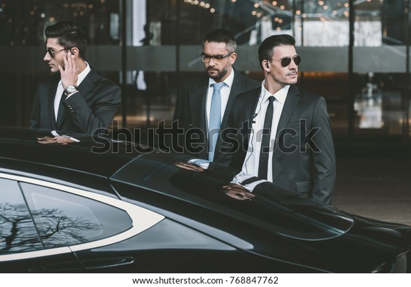 bodyguards going with businessman and reviewing\
territory near car