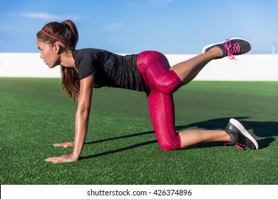 Bodyweight exercises - fitness woman doing fire hydrants legs kickbacks. Active girl training glute muscles raising one leg to the side and back for strength training in outdoor gym on grass floor.