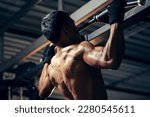 Bodyweight workout. Athletic pulling up showing back muscle at gym. Muscular man exercise pull up on bar in fitness gym.