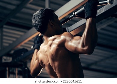 Bodyweight workout. Athletic pulling up showing back muscle at gym. Muscular man exercise pull up on bar in fitness gym.