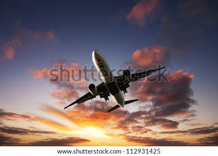 Boeing 777 jet aeroplane landing from bright dramatic sunset moody sky.