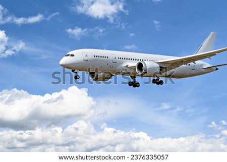 Boeing 787-8 Dreamliner passenger plane landing at the airport, under a blue sky with white clouds