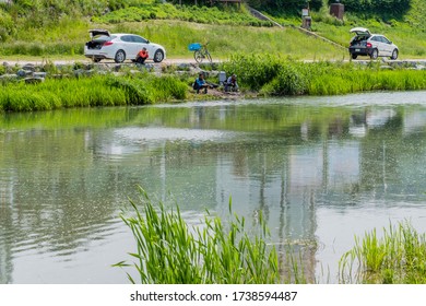 Boeun, South Korea; May 22, 2020: Unidentified Men Fishing From Riverbank In Public Park.