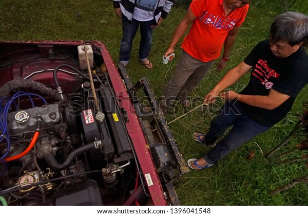 Bogor, West Java /\
Indonesia - January 21 2019: Men fix their car after doing off\
road, pulling winch, open the hood and see the engine captured low\
and top angles. 