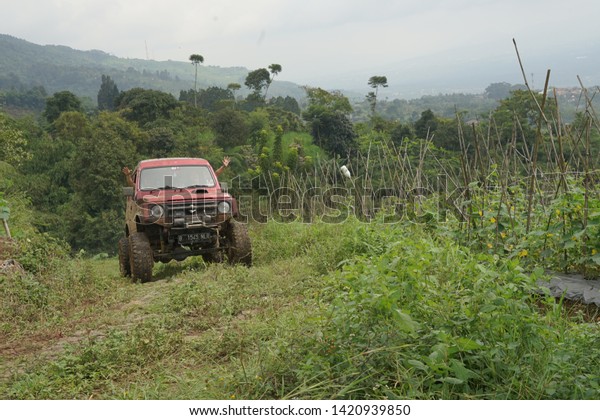 Bogor, West Java / Indonesia - January 2019: View of off\
road activity at a country involving all terrain cars captured\
after raining at muddy grassy route that makes participating cars\
dirty. 