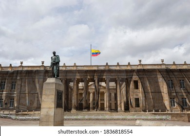 BOGOTA, COLOMBIA - OCTOBER 19 OF 2020 Bolivar Monument And Nariño's House With Midpole Colombian Flag At Bolivar Square With Cloudy Sky