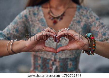 Bohemian chic gypsy woman wearing hands jewelry accessories and dress showing love sign. Boho detail close up  
