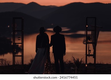 bohemian couple holding hands at a breathtaking sunset over the lake. After wedding. - Powered by Shutterstock