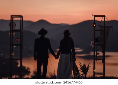 bohemian couple holding hands at a breathtaking sunset over the lake. After wedding. - Powered by Shutterstock