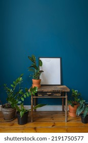 Bohemian Interior Style In Living Room With Vintage Side Table, Potted Houseplants, Mockup Picture In Black Frame, Blue Wall And Wooden Floor