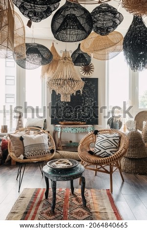 Bohemian living room with ethnic interior design. Vertical view of hygge house with home decor, natural material furniture, wicker armchair with cushions and wooden coffee table
