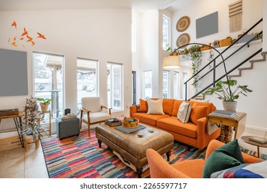 Bohemian style living room with orange sofa colored chairs books houseplants stair case and cluttered decor