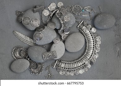 Bohemian style silver jewelry set and pebble on vintage grey background. Top view point.