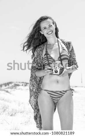 Bohemian vibe vacation. Portrait of happy hipster young woman in bikini on the beach with retro photo camera