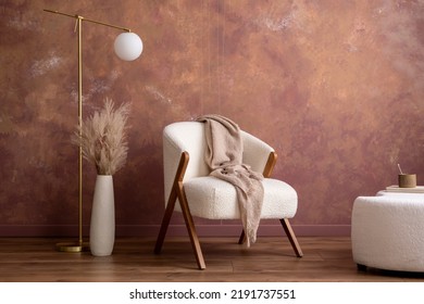 Boho composition a living room interior with white boucle  armchair, design pouf, lamp, vase with dried flowers, gold lamp and personal accessories. Cozy home decor. Template. Copy space.