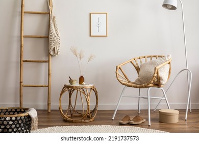 Boho and cozy interior of living room with design rattan armchair, pillows, mock up poster frame, side tables, lamp, bamboo ladder, decoration and personal accessories. Stylish home decor. Template.	