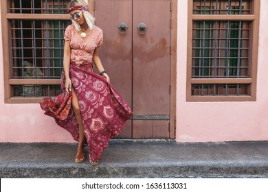 Boho girl in maxi skirt walking on the city street. Travelling in Phuket Old Town in Thailand.