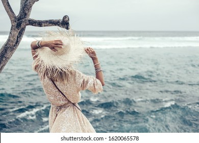 Boho Styled Model Wearing Dress, Straw Hat And Bag On The Beach In Bali