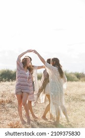 Boho Women Dancing In Circle In Sunny Rural Field