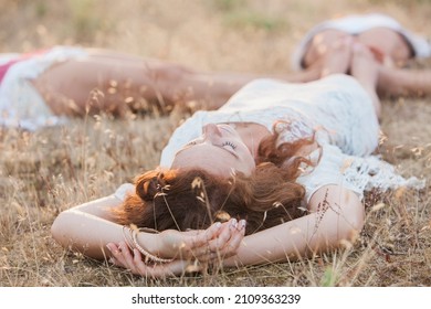 Boho women laying in circle with feet touching in rural field
