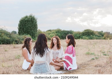 Boho women meditating in circle in rural field