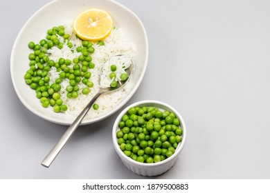 Boiled basmati rice with green peas in plate. Green peas in bowl. Copy space. Grey background. Flat lay
