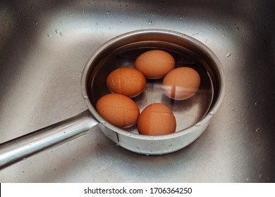 boiled chicken eggs lie in a ladle with cold water - Shutterstock ID 1706364250