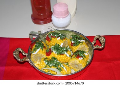 boiled corn cob on the table with salt, mayonnaise and ketchup