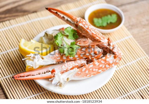 Boiled crab food on white plate and\
seafood sauce on the table / crab claws\
shellfish