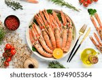 Boiled langoustines with parsley and spices on a plate. Norway lobster on a white wooden background. Top view. Free copy space.