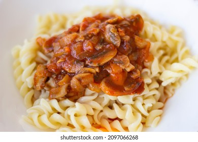 boiled macaroni pasta with Bolognese tomato meat sauce and mushrooms. Boiled pasta in white plate. Fusilli pasta with Bolognese tomato beef sauce. spiral macaroni with tomato sauce in white bowl. 