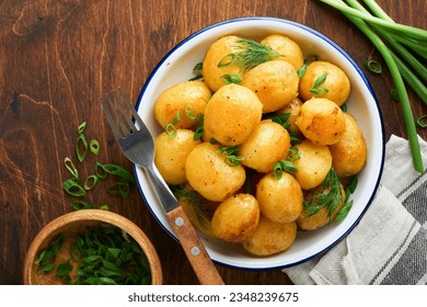 Boiled new or young potatoes with butter, fresh dill and onions in white bowl on dark old rustic wooden background. Tasty new boiled potatoes. Top view. - Powered by Shutterstock