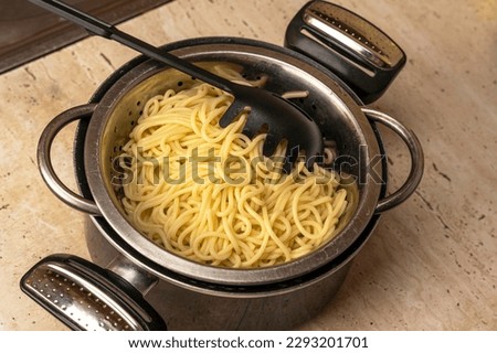 boiled ready-made spaghetti in a colander and a kitchen saucepan