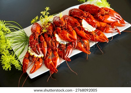 Boiled red crayfish with dill and lemon slices on white plate, dark background, traditional seafood appetizer, swedish crayfish party, gourmet