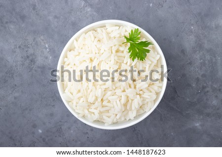 Boiled rice in a bowl on gray background.