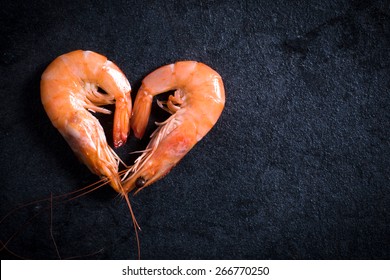 Boiled tiger shrimps heart shape on table with blank space on the right side 
