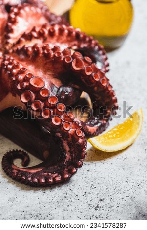 boiled whole octopus on a gray stone with lemon and pink pepper.