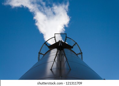 Boiler chimney with its smoke on the clear blue sky background